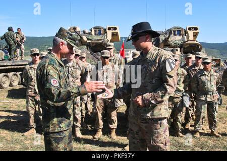 Us-Armee Kapitän Nicholas Spicocchi, Kommandeur der Alpha Company, 2nd Battalion, 5th Cavalry Regiment, 1st Armored Brigade Combat Team, 1.Kavallerie Division, gibt Bulgarische Col. Stojan Georgiev Schopow, 2. mechanisierten Brigade Stabschef, eine Münze als Zeichen der Anerkennung bei der Abschlussfeier der Übung Platin Löwe, eine jährliche Übung, fördert die regionale Stabilität und baut dauerhafte Beziehungen mit Partnerstaaten, bei der Abschlussfeier, Novo Selo, Bulgarien, 9. August 2018. Diese Übung ist zur Unterstützung der Atlantischen lösen, ein bleibendes Training bet Stockfoto