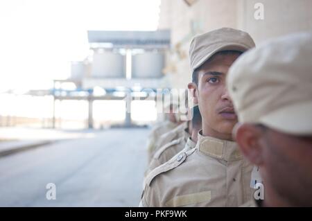 Eine syrische Demokratischen Kräfte trainee wartet im Einklang, wie Er und Hunderte mehr vorbereiten, als Teil einer Überprüfung durch die SDF-in der Nähe von Shaddadi, Syrien, 1. August 2018 Led überprüft werden. Dies ist ein entscheidender Schritt im Einstellungsverfahren, um sicherzustellen, dass die Auszubildenden für die Aufgabe geeignet sind als die SDF-bereitet die endgültige ISIS Hochburg im nahen Fluss Euphrat Valley zu löschen. Stockfoto