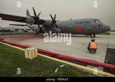 MAFFS 4, ein modulares System zur Brandbekämpfung aus der Luft C-130J Hercules Flugzeugen aus den 146 Airlift Wing, California Air National Guard ausgestattet, kommt an der U.S. Forest Service San Bernardino Airtanker Base, in San Bernardino, Kalifornien, Aug 8, 2018, staatliche Ämter kämpfen das heilige Feuer in Orange und Riverside Grafschaften zu unterstützen. Stockfoto