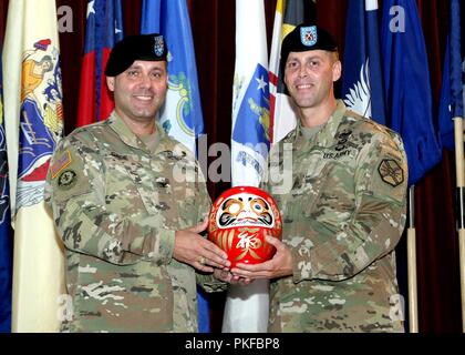 Command Sgt. Maj. Billy J. Norman, U.S. Army Garrison Japan command Sergeant Major und Oberst Phillip K. Gage, garrison Commander, präsentieren die Daruma Puppe zu jenen, die am 10.08.Übernahme von Verantwortung Zeremonie anwesend sind, im Camp Zama Gemeinschaft Club. Daruma, einem Japanischen Symbol von Glück ist durch eine gewichtete unten geprägt, so dass es immer wieder in eine aufrechte Position, wenn es ist umgekippt. Die Augen eines neuen Daruma sind unlackiert. Die Person, die Farben in einem Auge beim Beten für die Erfüllung von einigen besonderen Wünschen. Sie legen Sie dann die Daruma in der Familie Schrein oder die Stockfoto