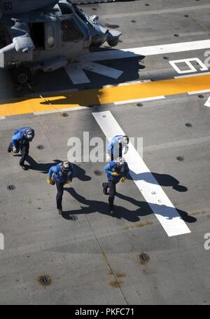 Pazifik (Aug. 10, 2018) eine Abteilung Matrosen Rückzug aus einem MH-60S Sea Hawk, der "Blackjacks" der Hubschrauber Meer Combat Squadron (HSC) 21, nachdem sie die Helikopter in das Flight Deck der Amphibisches Schiff USS BONHOMME RICHARD (LHD 6) bei vertikaler Auffüllung Ausbildung zugewiesen. Bonhomme Richard ist derzeit in den USA 3 Flotte Bereich der Operationen. Stockfoto