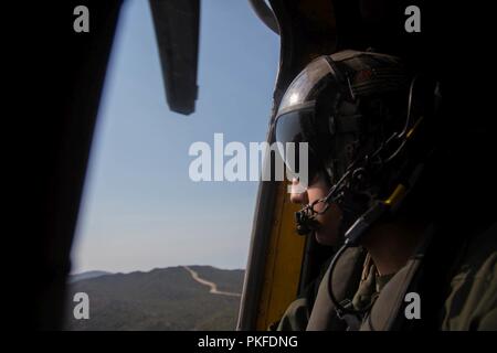 Sgt. Xavier Rodriguez, eine Crew Chief mit Marine schweren Helikopter Squadron (HMH) 465, Marine Flugzeuge Gruppe 16, 3. Marine Flugzeugflügel, das Gelände Scans von einem CH-53E Super Stallion Hubschrauber über Marine Corps Base Camp Pendleton, Calif., Aug 10. Während des Fluges, crew Chiefs sind Experten auf Flugzeuge und Gelände. HMH-465 führt das Training mit Amphibischen Raids Zweig, Expeditionary Operations Training Gruppe, ich Marine Expeditionary Force, Infanterie Marines schnell durchführen - Seil von einem Hubschrauber. Stockfoto