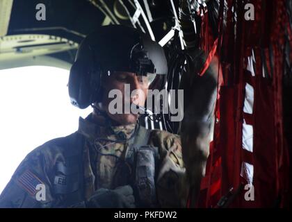 Us-Armee Sgt. Nathan Eberhardt, Crew Chief, 2. Allgemeine Unterstützung Aviation Battalion, 135 Aviation Regiment, Colorado Army National Guard, verwendet seinen internen Mikrofon während der Übung Northern Strike 18 in Alpena Mich., Aug 9, 2018 die Crew der CH-47 Chinook Hubschrauber zu sprechen. Reiten entlang auf die Chinook waren Offiziere der Royal Jordanian Air Force, die arbeiteten, neben ihren Colorado Army National Guard aviation Kollegen Luft-Integration von Best Practices zu teilen und ihre Beziehung stärken. Stockfoto