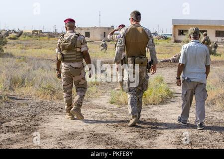 Ein Neuseeland Defence Force Mitglied, mit Task Group Taji, Wanderungen mit einem Bagdad Kampfschule Tauchlehrer während urban Operations Training mit irakischen Armee 59th Brigade im Camp Taji, Irak, 25. Juli 2018. Die irakischen Sicherheitskräfte sind das Fundament für die Zukunft des Irak durch die Verbesserung ihrer Fähigkeiten, um ein sicheres und stabiles Umfeld für ihre Nation zu stellen. Stockfoto