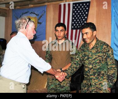 Larry Bartlett, Senior Advisor für die syrische Übergangshilfe Response Team, schüttelt Hände mit Welat Eto, ein Verbindungsbüro in der Joint Operations Center in Manbij, Syrien, 9. August 2018. Das Joint Operations Center ermöglicht Mitgliedern der Manbij militärischen Rat, die zivile Verwaltung der Manbij Manbij, der inneren Sicherheit und Koalition Berater für alle zusammenarbeiten, um den Frieden in Manbij zu gewährleisten. Stockfoto