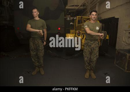 Pazifik (8. August 2018) - kpl. Aaron Spaulding (rechts), eine Infanterie machine Gunner mit Bataillon Landung Team 3/1, und Cpl. Wyatt Navarro, eine Aviation ordnance Marine mit Marine Medium Tiltrotor Squadron 166 verstärkt, 13 Marine Expeditionary Unit (MEU), praxis Schwert Handbuch an Bord der San Antonio-Klasse amphibious Transport dock USS Anchorage LPD (23), die während einer planmäßigen Einsatz der Essex Amphibious Ready Group (ARG) und 13 MEU. Das Essex ARG/13 MEU ist ein fähiger und tödliche Navy-Marine Corps Team der 7 Bereich der Flotte im Einsatz regionaler St zu unterstützen. Stockfoto