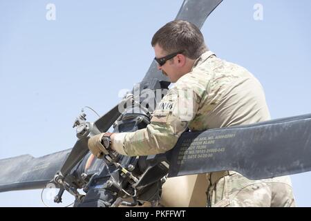 KANDAHAR AIR WING, Afghanistan (Aug. 5, 2018) ein Zug, Beraten und Unterstützen Command-Air pilot Advisor prüft ein UH-60 vor Beginn einer Mission Qualifizierung Training Mission August 5, 2018, Kandahar Air Wing, Afghanistan. Nach Abschluss der Mission Qualifizierungsmaßnahmen, afghanischen Luftwaffe Piloten in der Lage, Kampfhandlungen, Tag oder Nacht, in jeder Umgebung. Stockfoto