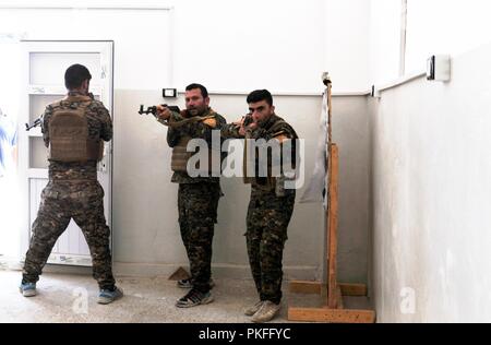 Mitglieder der Manbij militärischen Rat klar die Ecken eines Raumes, die bei einer Bewertung von Close Quarters Battle Bohrer in Manbij, Syrien, 10. August 2018. Während der Bewertung, Mitglieder der MMC hatten ihre Fähigkeit, ein Gebäude und klare mehrere Zimmer zu demonstrieren. Stockfoto