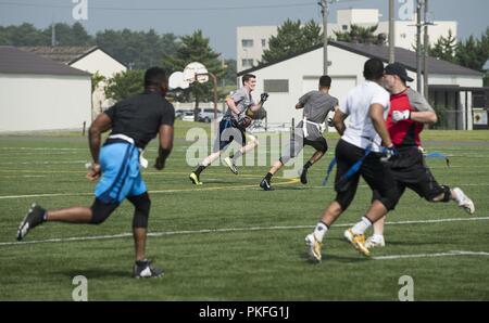 Us Air Force Airman 1st Class Kevin Cheeseman, Mitte, ein 35Th medizinischen Operationen Squadron für Luft- und Raumfahrt Medizintechnik, läuft der Ball während eines Spiels der Flag Football an Misawa Air Base, Japan, 27. Juli 2018. Flag Football war einer von 16 Ereignisse, die während der zweiten jährlichen Team Misawa belastbaren Beziehungen und Anerkennung Tag nahm. Stockfoto