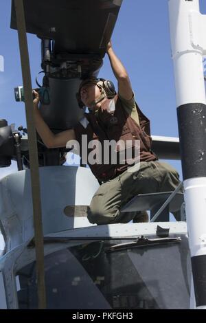 Pazifik - US Marine Cpl. Joaquin Barrios, Ein UH-1Y Venom Crew Chief mit Marine Medium Tiltrotor Squadron 166 verstärkt, 13 Marine Expeditionary Unit (MEU), installiert eine Blade Stift auf einer UH-1Y Venom an Bord der San Antonio-Klasse amphibious Transport dock USS Anchorage LPD (23), die während einer planmäßigen Einsatz der Essex Amphibious Ready Group (ARG) und 13 MEU, 4. August 2018. Das Essex ARG/MEU Team ist eine starke, flexiblen, reaktionsschnellen und gleichbleibende Kraft in der Lage, Manöver Kriegsführung in allen Domänen; es ist ausgestattet und beliebig skalierbar von der humanitären Krise assista zu reagieren Stockfoto