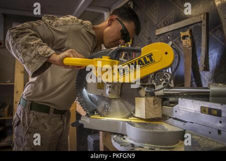 Unbekannten ORT, Südwesten Asien - US Marine Corps LCpl. Diego Brevillard, ein Ingenieur Ausrüstung Fahrer mit 3 Bataillon 7. Marine Regiment zu speziellen Zweck Marine Air-Ground Task Force angebracht, Krise Response-Central Befehl (SPMAGTF-CR-CC), schneidet ein Board für eine Sicherheit nach Juli 25, 2018. SPMAGTF-CR-CC Marines regelmäßig Unterstützung Task Force spartanisch eingerichtet, deren Aufgabe es ist, die irakischen Sicherheitskräfte beraten und in Ramadi Bereich unterstützen. Stockfoto