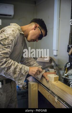 Unbekannten ORT, Südwesten Asien - US Marine Corps LCpl. Diego Brevillard ein Ingenieur Ausrüstung Fahrer mit 3 Bataillon 7. Marine Regiment zu speziellen Zweck Marine Air-Ground Task Force angebracht, Krise Response-Central Befehl (SPMAGTF-CR-CC) Hammer einen Nagel in eine Struktur für eine Sicherheit nach Juli 25, 2018. SPMAGTF-CR-CC Marines regelmäßig Unterstützung Task Force spartanisch eingerichtet, deren Aufgabe es ist, die irakischen Sicherheitskräfte beraten und in Ramadi Bereich unterstützen. Stockfoto