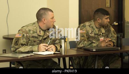 Us-Armee Maj. Stephen Raschke, und Maj Navin Kalicharan, beide Operationen 369 Sustainment Brigade zu einem Punkt in einer kurzen während Liberty Hunter Warfighter Übung in Fort Drum hören, als Teil des 369 Fort Drum und Camp Smith, N.Y., dual Ort jährliche Übung August 16, 2018. Hundert und 75 New York Army National Guard Soldaten aus 369 Sustainment Brigade nahm an jährlichen Ausbildung an zwei Standorten, Fort Drum und Camp Smith, N.Y., August 9-18, 2018. Stockfoto