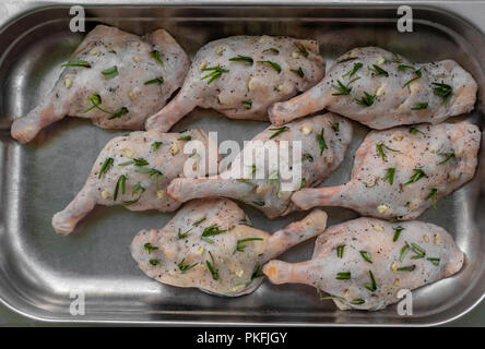 Raw Entenschenkel gefüllt mit Rosmarin und Knoblauch in einem Metallauflagefach Stockfoto