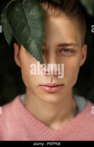 Natürliche Portrait von einem gutaussehenden jungen Mann mit Sommersprossen mit grünen Blättern Stockfoto