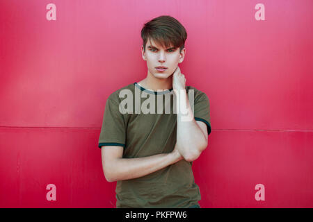 Hübscher junger Mann in trendigen Sommer Kleidung in der Nähe von einem hellen rosa Wand Stockfoto