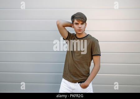 Hübscher junger Mann in einem Fashion T-Shirt in der Nähe der graue Wand Stockfoto