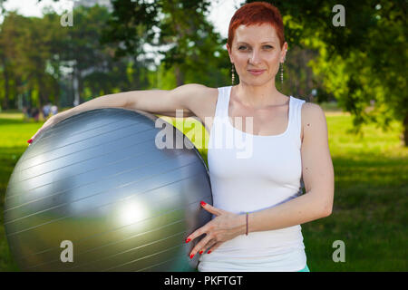 Pilates, Freizeit in der Natur, Fitness Ball trainieren - schöne weibliche Fitness Instructor Holding ein Pilates Ball unter den Arm, aktiv Sport lifest Stockfoto