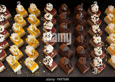 Kleine Schokolade und Vanille geschichteten Kuchen in den Zeilen auf Süßigkeit Buffet. Süße Paradies. Stockfoto