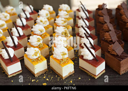 Kleine Schokolade und Vanille geschichteten Kuchen in den Zeilen auf Süßigkeit Buffet. Süße Paradies. Stockfoto