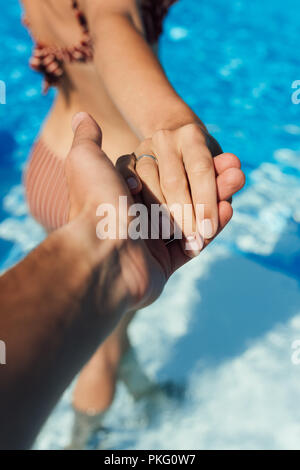 7/8 shot der Mann die Hand der Frau im Pool, Follow me Konzept Stockfoto