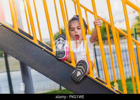Das Bein eines niedlichen kleinen Mädchen heraus aus einer Metalltreppe Bars auf dem Spielplatz Stockfoto