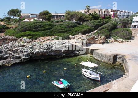 Spanien. Balearen. Menorca. Binebeca. Binebequer-Vell. Cove mit Fischerbooten und Hotel Komplex. Stockfoto