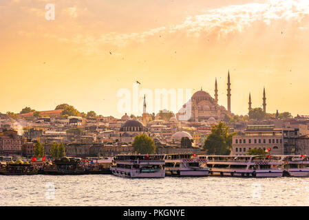 Eminonu Port mit Schiffen und Suleymaniye Moschee im Stadtteil Fatih am Goldenen Horn Fluss vor Sonnenuntergang, Istanbul, Türkei. Travel Concept und Meer Fron Stockfoto