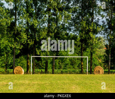 Stroh Bälle auf jeder Seite eines alten rostigen Fußballtor in einem Feld, Puy de Dome Abteilung, Auvergne Rhône-Alpes, Frankreich Stockfoto