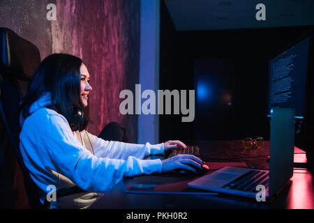 Fröhliche junge Frau Freelancer in Freizeitkleidung eingeben Programmierung Code arbeiten an modernen Laptop Computer zu Hause. Positive student Aktualisieren von Software auf Netbooks. Stockfoto