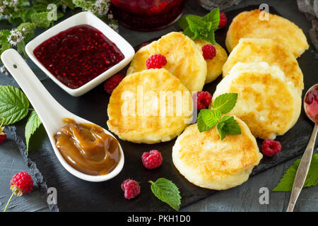 Frühstück Hintergrund. Hausgemachten Quark Pfannkuchen mit Kondensmilch, himbeermarmelade auf Schiefer. Stockfoto