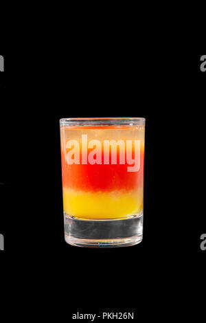 Mehrfarbig geschichtete Cocktail, Glas mit transparenten und farbigen Getränk, mit dem Geschmack der Tomate, Zitrone, alkoholische, Seitenansicht isolierte schwarze backgrou Stockfoto