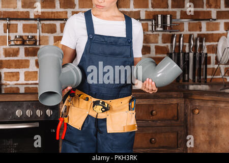 7/8 shot der weiblichen Klempner mit Kunststoff Rohre in Küche Stockfoto