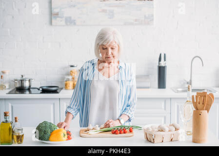 Portrait von älteren Dame Schneiden von Gemüse beim Kochen Abendessen am Tresen in der Küche Stockfoto