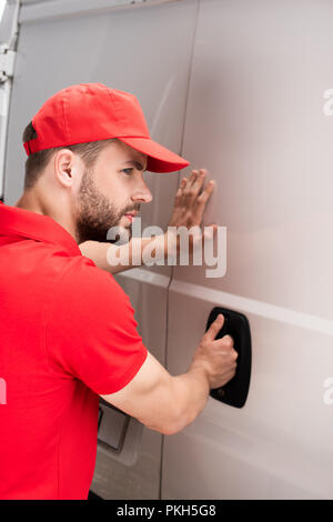 Seitenansicht des jungen Delivery Man van Tür öffnen Stockfoto