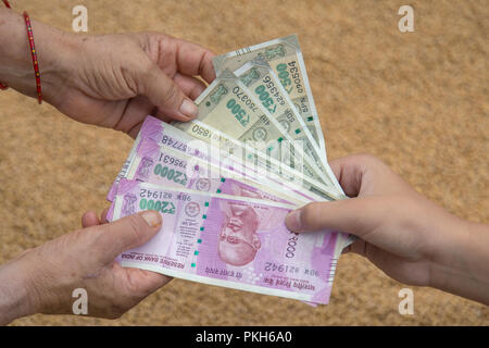 Hand geben Indische 500 und 2000 Rupien Banknoten über Weizen Hintergrund. Konzept für das Ergebnis oder verbringen Sie in der Landwirtschaft. Stockfoto