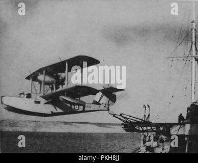 Ein altes Foto auf Papier mit einer experimentellen Flugzeugträger mit einem Britischen biplanar (Wasserflugzeug) von einem Kriegsschiff 1933 gestartet Stockfoto