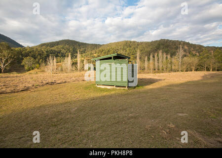 Holz- gebäude mit Grube wc im Feld neben der bewaldete Hügel im ländlichen Campingplatz in NSW Australien NSW Stockfoto