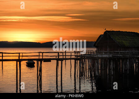 Bunte Landschaft mit einer alten Hütte, auf hölzernen Säulen über dem Wasser gebaut, am Bodensee, bei Sonnenuntergang, in Uhldingen-Mueldorf, Deutschland. Stockfoto