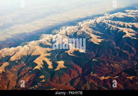 Luftaufnahme von majestätischen Karpaten Gebirge mit schneebedeckten Gipfeln und Hügeln, grünen und roten Wald, Felder. Sonnigen, wolkenlosen Herbst Tag. Shot Abo Stockfoto