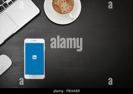 Kiew, Ukraine - Februar 6, 2018: Apple iPhone 8 plus Mit Linkedin App auf dem Bildschirm auf schwarz Schreibtisch mit Kopfhörern, MacBook und iPad, Ansicht von oben. Linke Stockfoto