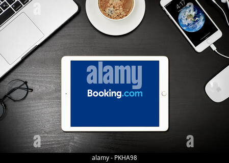 Kiew, Ukraine - Februar 6, 2018: Apple iPad Gold mit Booking.com App auf dem Bildschirm auf schwarz Schreibtisch mit dem MacBook und iPhone, Ansicht von oben. Booking.com ist Stockfoto