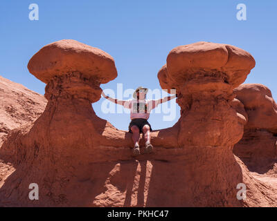 Besucher sitzt zwischen zwei Goblins, Goblin Valley State Park, Hanksville, Utah. Stockfoto