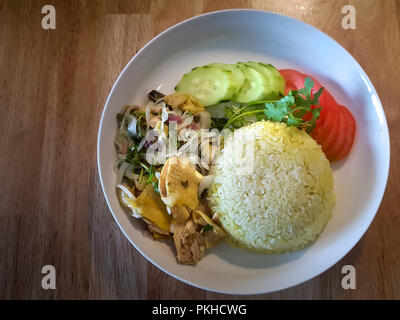 Reis in Hühnerbrühe mit ein klein wenig Gelbwurz für Farbe gekocht, in einem Wok geworfen und serviert mit gekocht, grob Hühnerfleisch Stockfoto