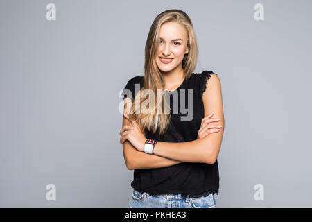 Portrait von sehr trendy Frau mit dem strahlenden Lächeln mit verschränkten Armen an der Kamera auf grauem Hintergrund suchen Stockfoto