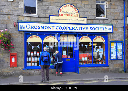 Ein paar Wanderer außerhalb Grosmont Genossenschaft Ltd, Britain's älteste unabhängige Genossenschaft, Grosmont, North Yorkshire, England, UK. Stockfoto