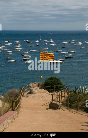 Die katalanische Flagge mit dem blauen Meer und Boote im Hintergrund an einem sonnigen Tag. Vertikaler, d Calella Calella, Costa Brava, Spanien. Stockfoto