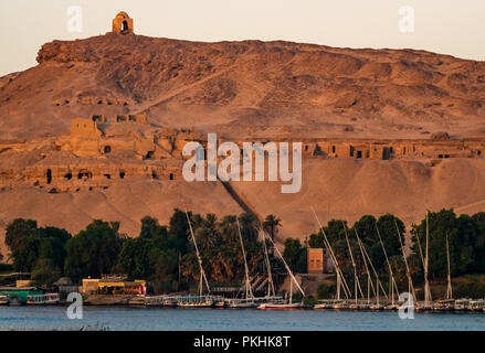 Hilltop muslimischen Propheten grab Qubbet el-Hawa in der frühen Morgen über alte Fels gehauene Gräber mit einer Feluke segeln Boote, Nil, Assuan, Ägypten, Afrika Stockfoto