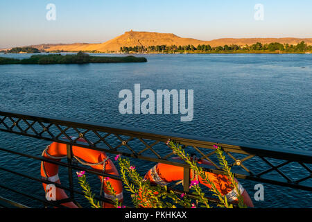 Blick vom Kreuzfahrtschiff Deck der alte Noble Gräber in Qubbet el-Hawa in Cliff und Feluke segeln Boote, Nil, Assuan, Ägypten, Afrika Stockfoto