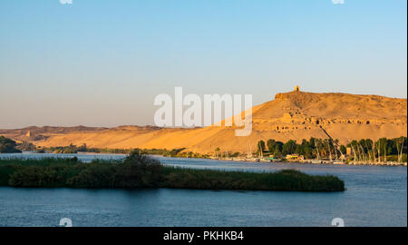 Aga Khan Mausoleum und Hilltop Qubbet el-Hawa Grab im Morgenlicht mit traditionellen Feluke segeln Boote, Nil, Assuan, Ägypten, Afrika Stockfoto